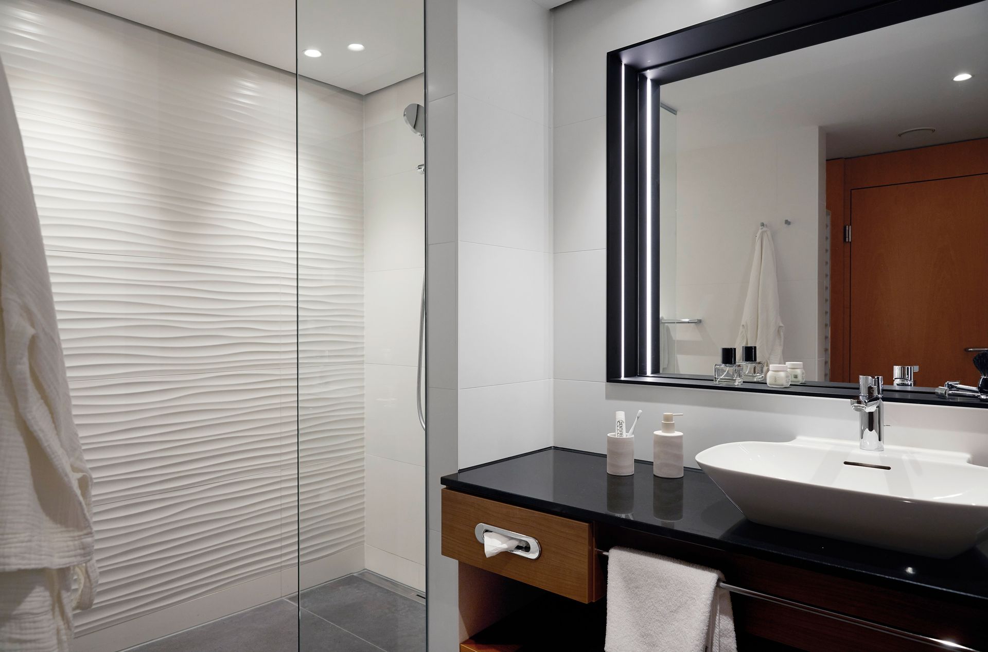 A bathroom with a sink a mirror and a walk in shower