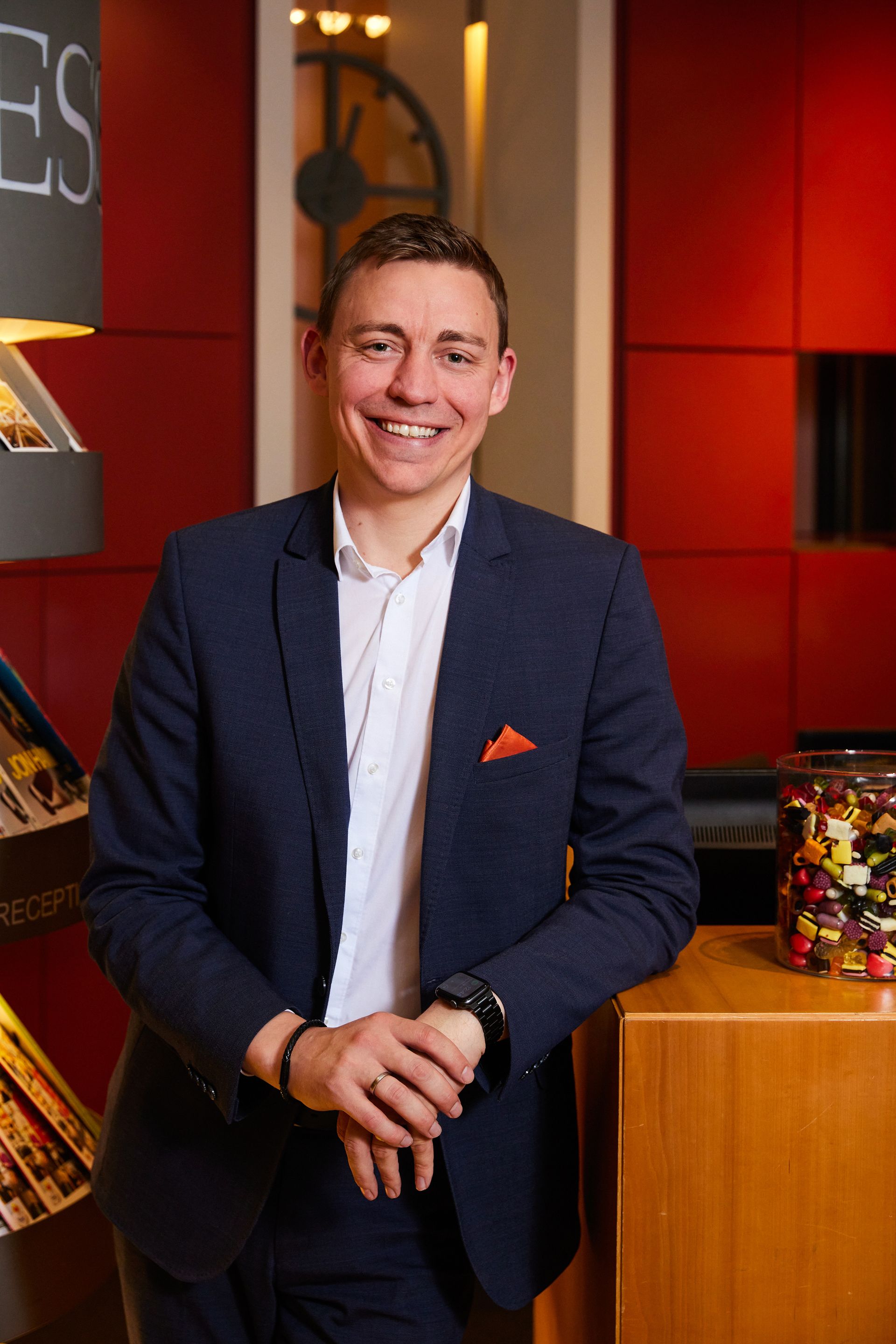 Ein Mann im Anzug steht vor einem Glas mit Bonbons.