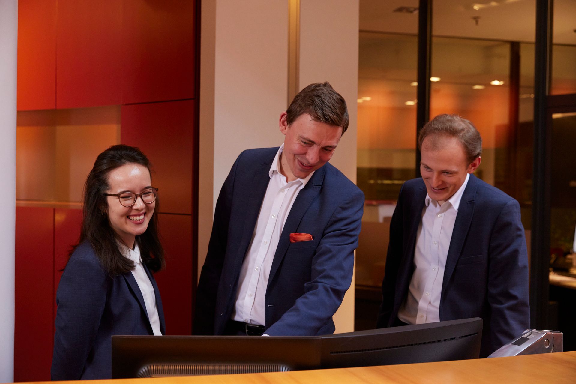 Eine Gruppe von Menschen in Anzügen schaut auf einen Computerbildschirm.