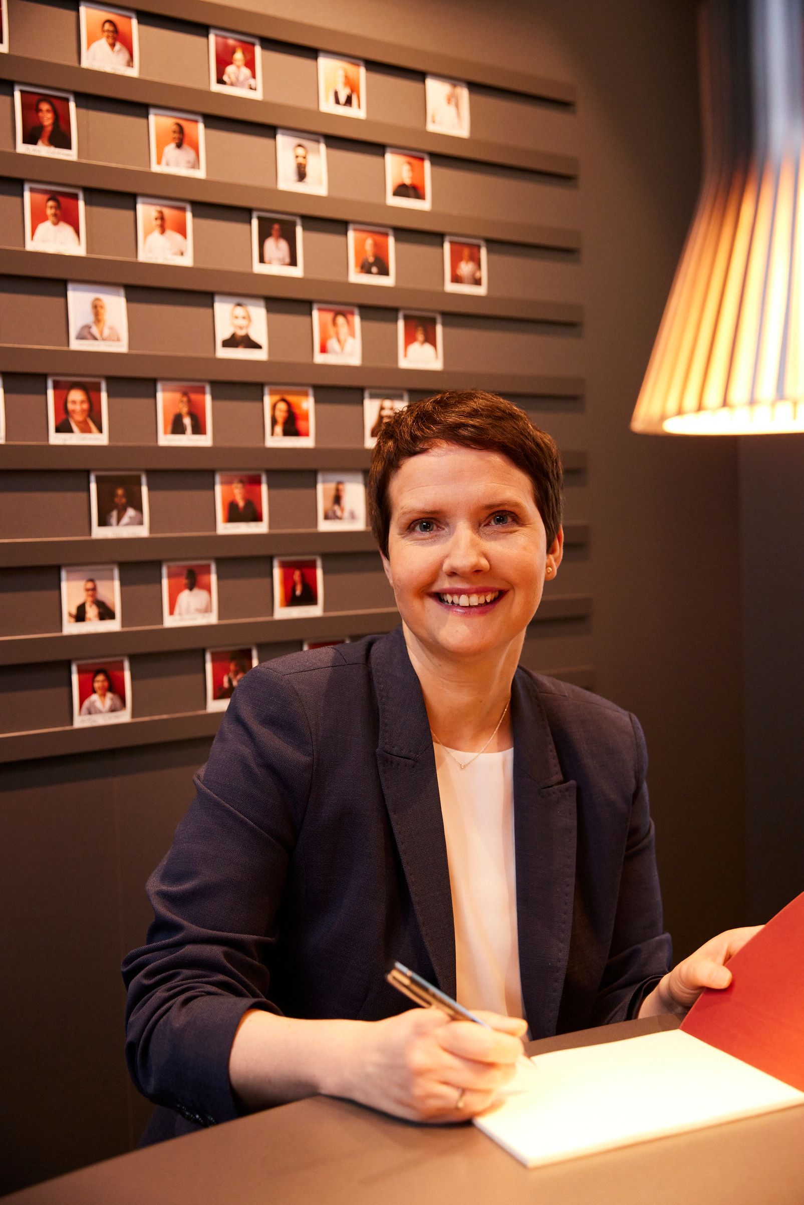 Eine Frau sitzt an einem Schreibtisch mit einem Stift in der Hand