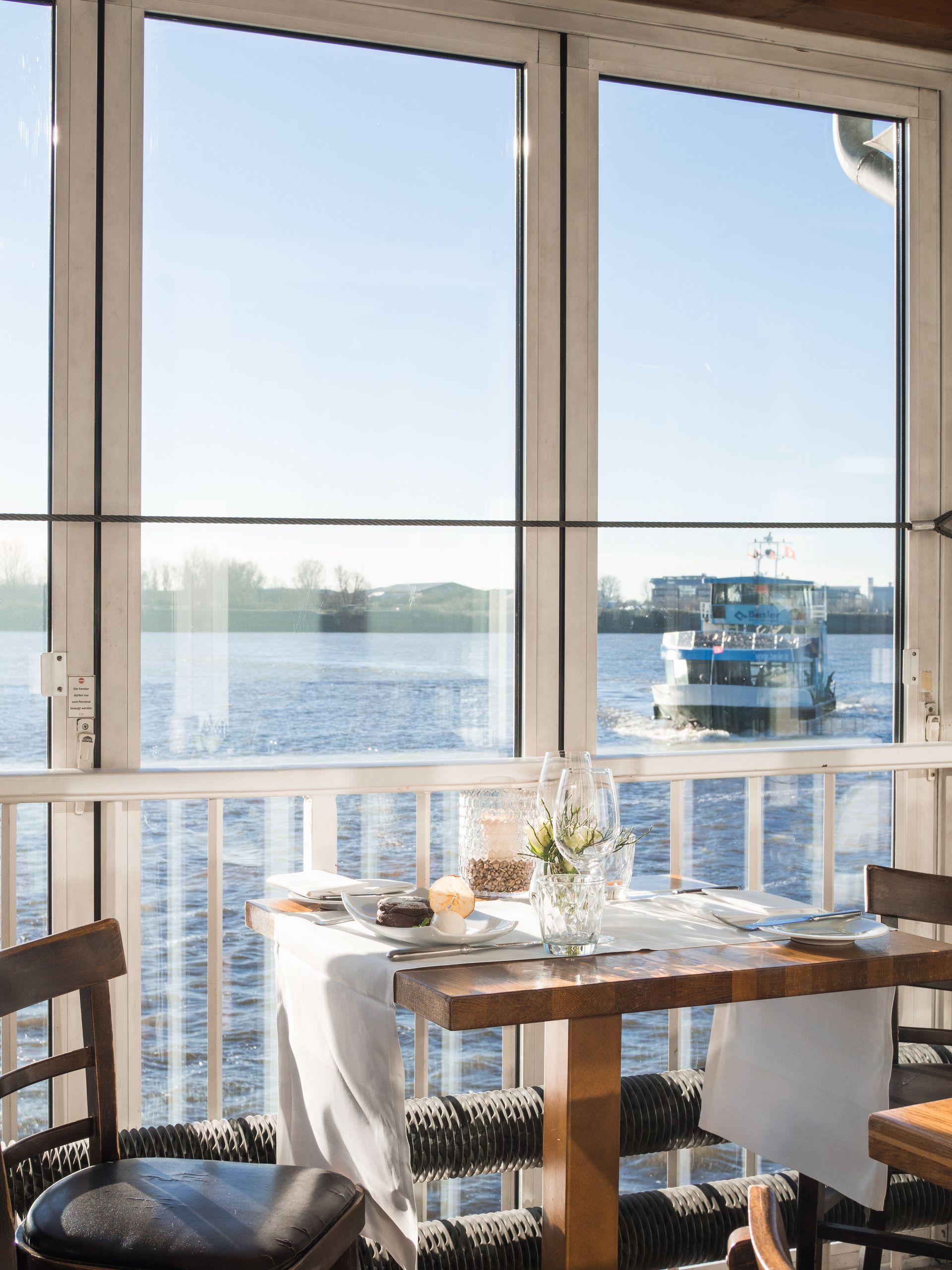 Ein Tisch und Stühle vor einem Fenster mit Blick auf ein Gewässer