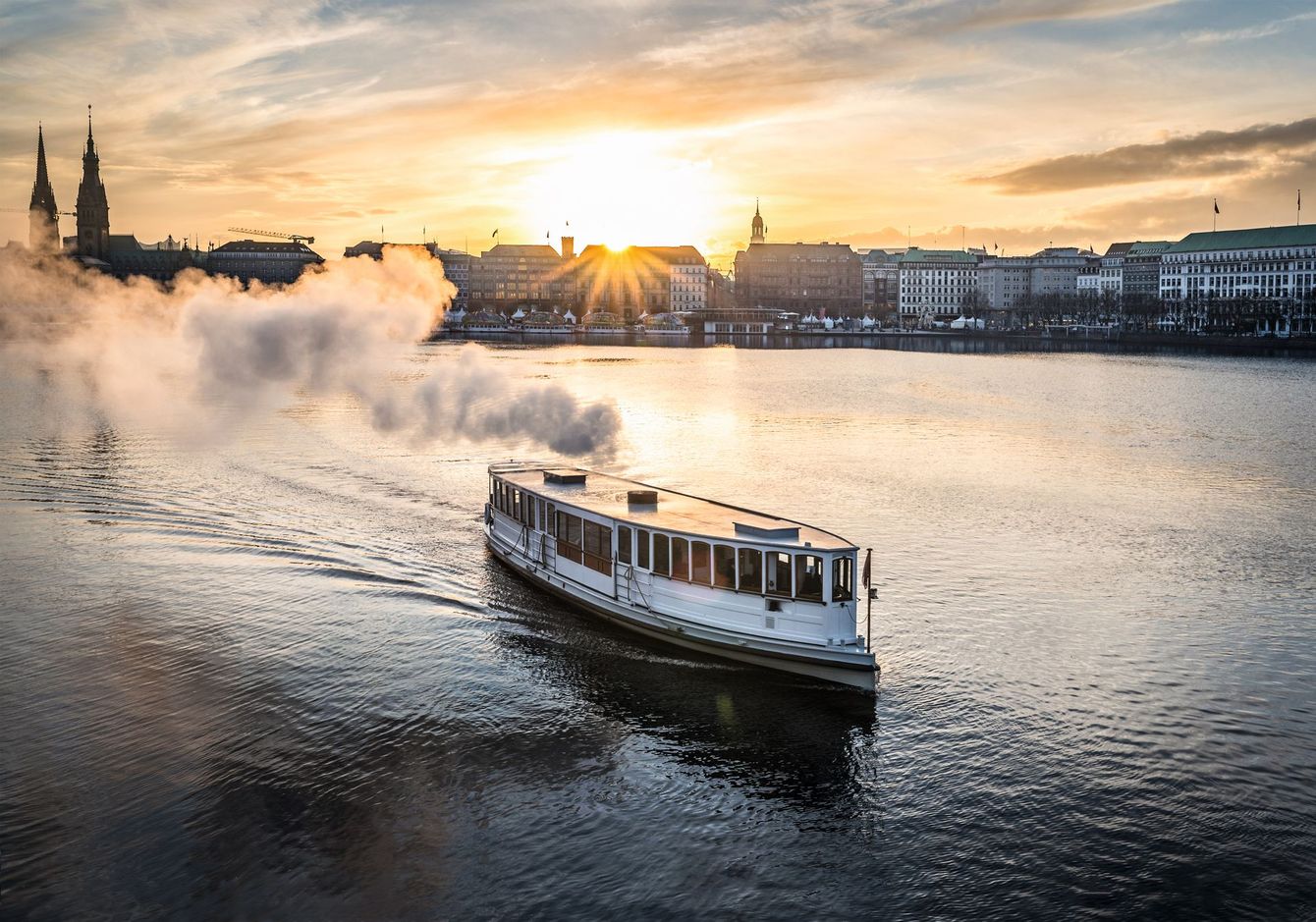 Bei Sonnenuntergang schwimmt ein Boot auf einer Wasserfläche.