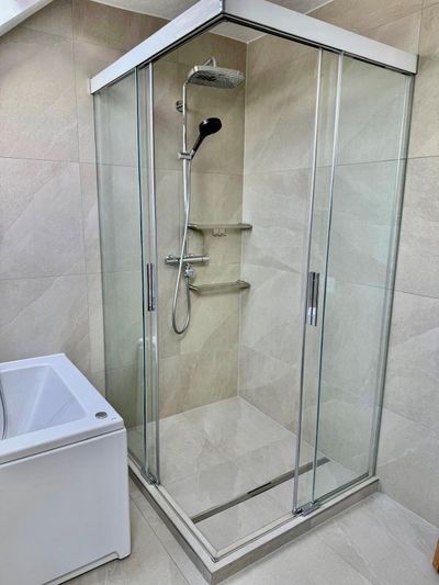 Outils de plomberie sur le sol carrelé d'une salle de bain, à côté d'un lavabo et de tuyaux apparents.