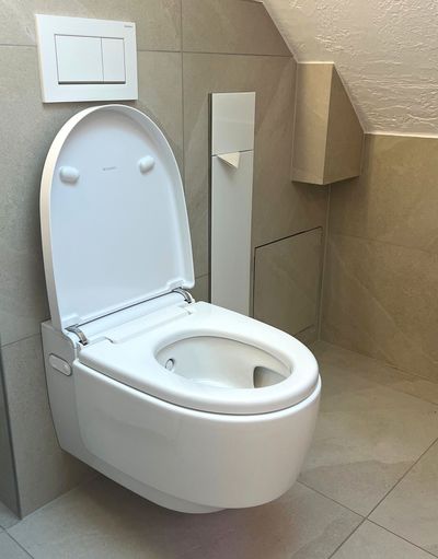 Toilettes modernes avec siège de bidet et robinet de chasse chromé dans une petite salle de bain