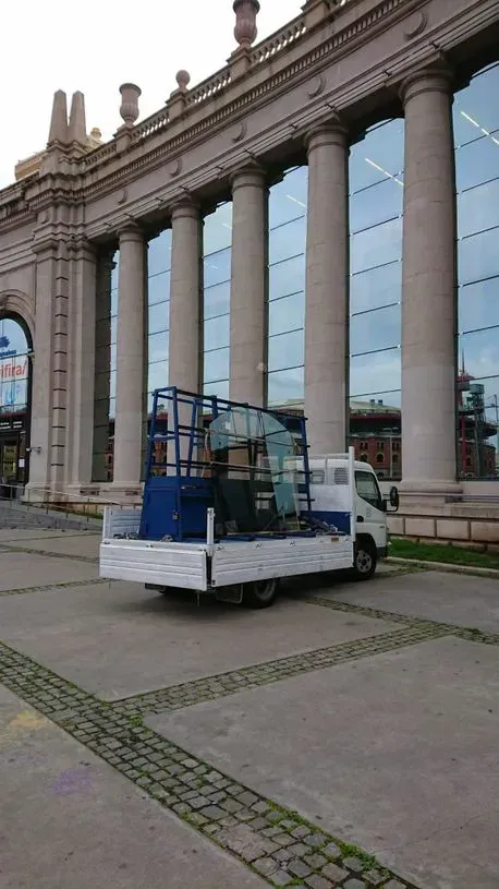 Un camión blanco con una escalera en la parte trasera está estacionado frente a un edificio.