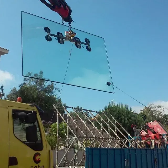 Un gran trozo de vidrio está siendo levantado por una grúa.