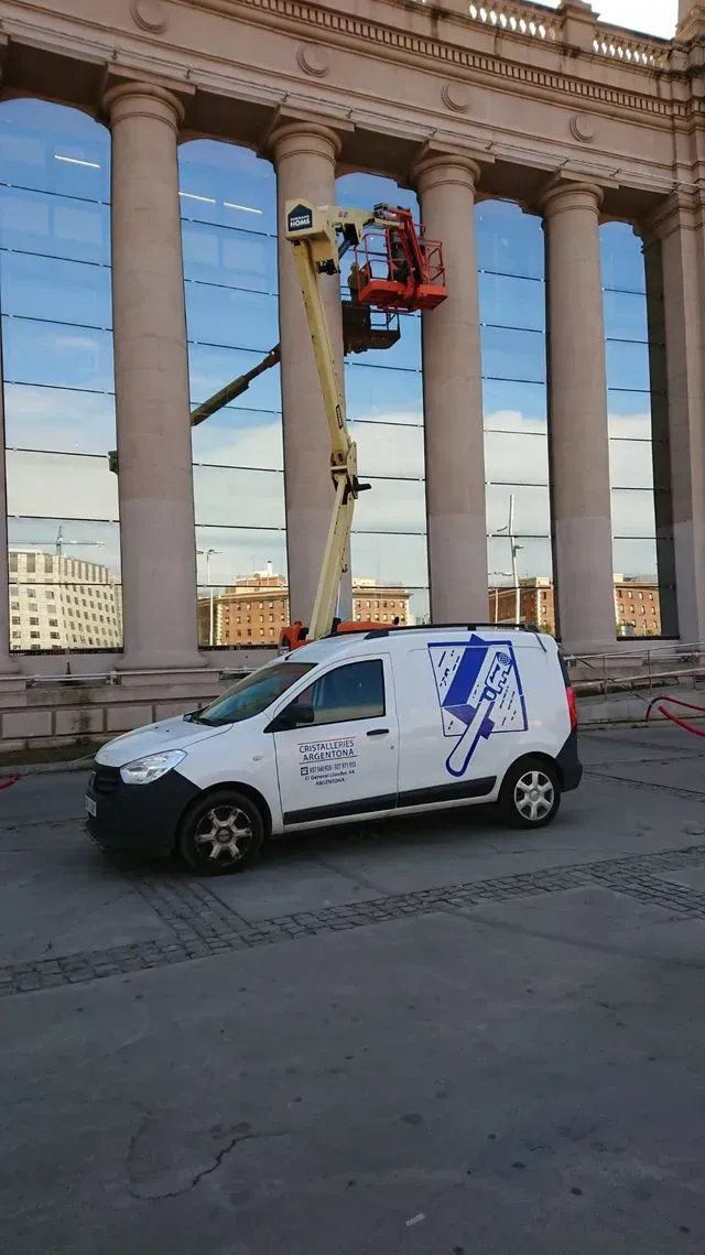 Una camioneta blanca está estacionada frente a un edificio con columnas.