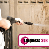 Una persona sostiene una hidrolavadora para limpiar una pared, con el logotipo de