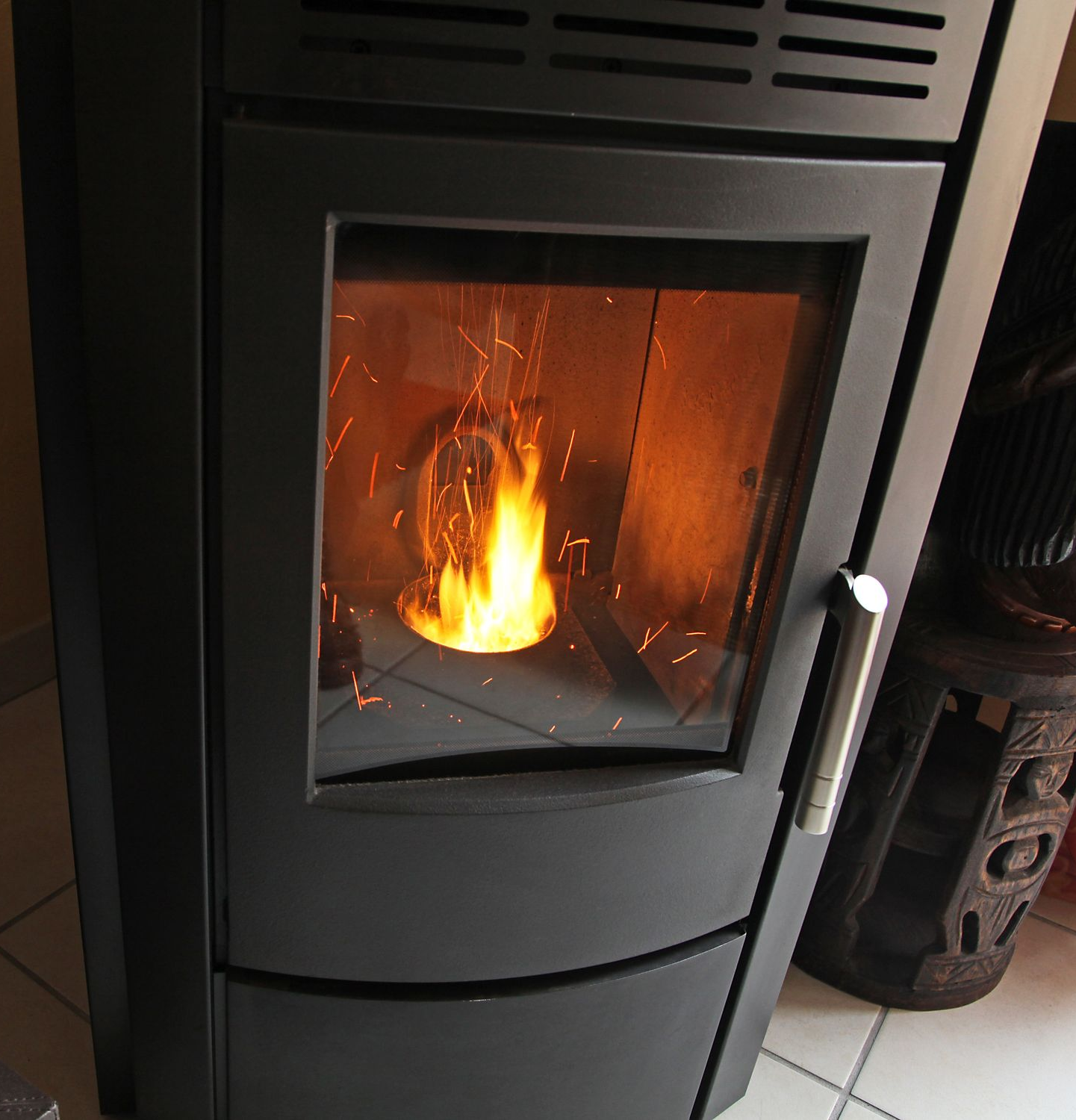 Un poêle à granulés en combustion, dont les flammes orange sont visibles à travers la porte vitrée.