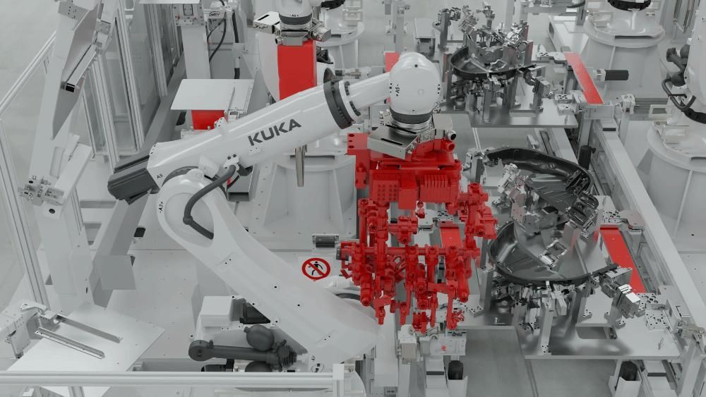 Un brazo robótico KUKA blanco en un entorno industrial, levantando un componente de montaje de metal rojo en una fábrica.
