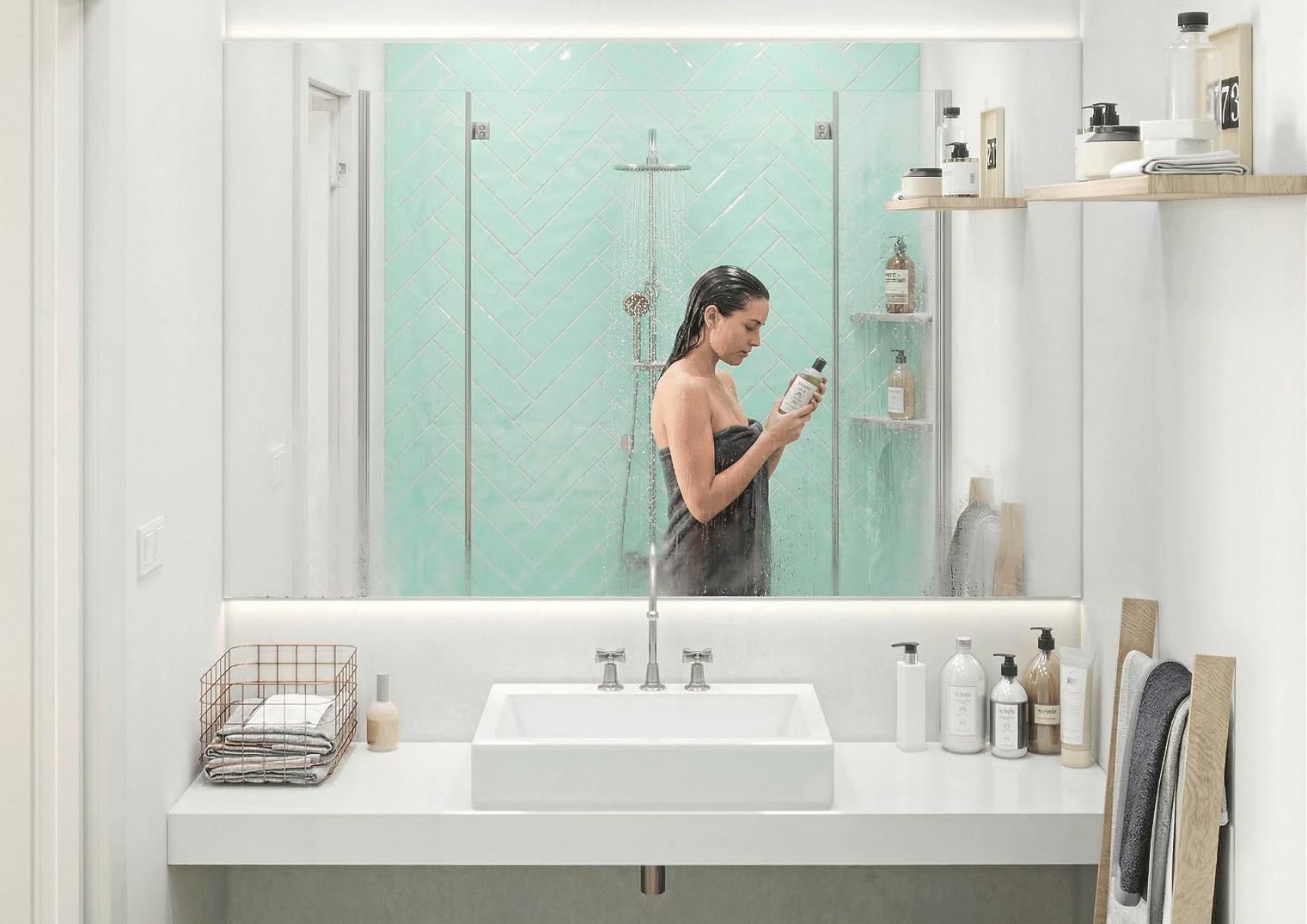 Una persona envuelta en una toalla, de pie frente al espejo del baño, lee la etiqueta de una botella.