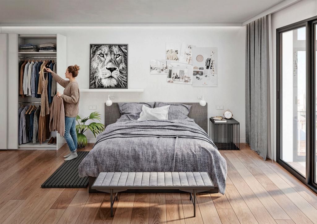 Una persona eligiendo ropa de un armario en un dormitorio moderno con una cama grande, decoración neutra y ventanales 