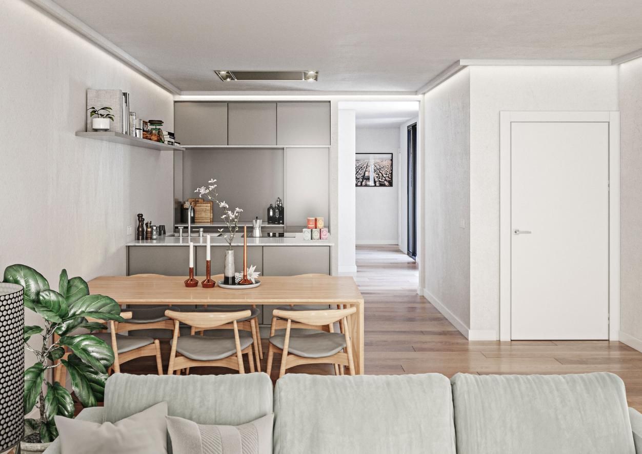 Comedor moderno con mesa y sillas de madera, y cocina al fondo, visto desde detrás de un sofá gris claro.