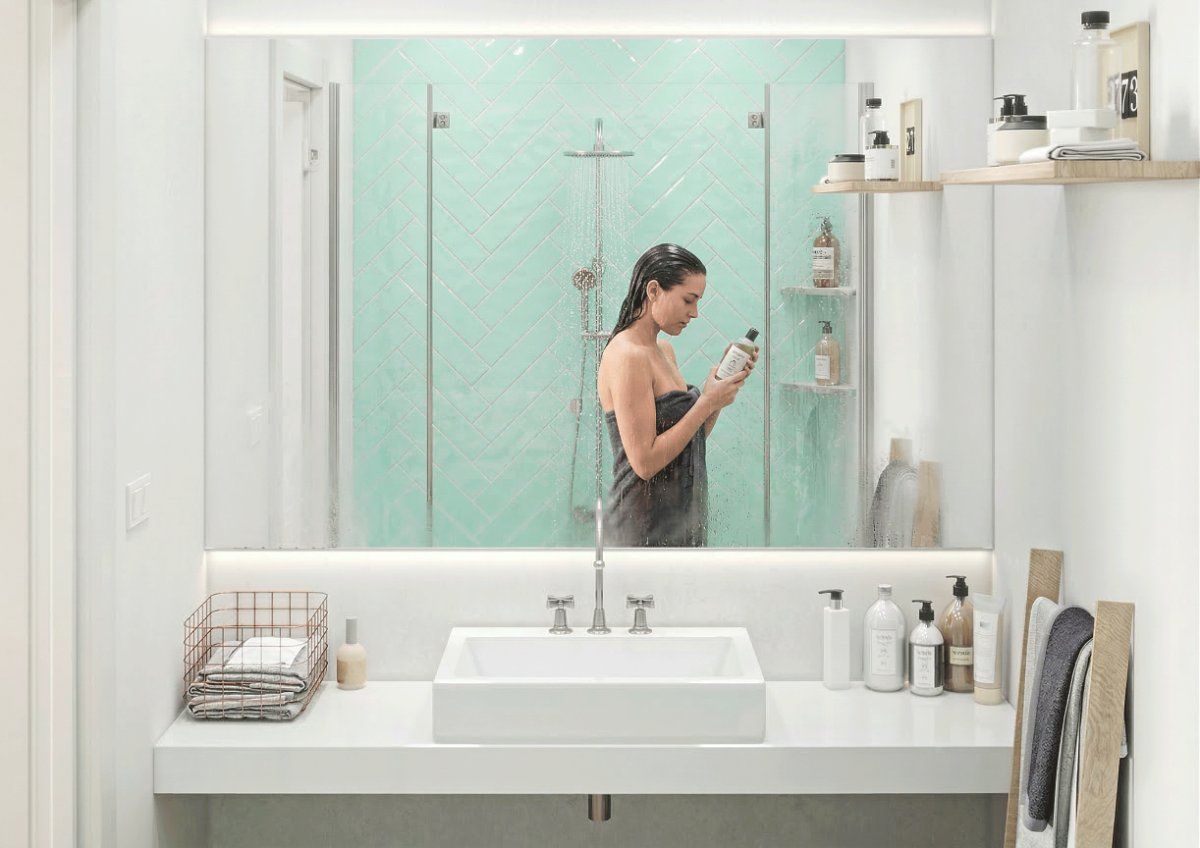 Una persona envuelta en una toalla gris se encuentra en un baño moderno de tonos claros