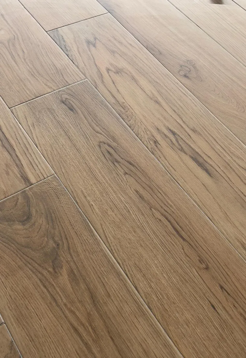 Suelo de tablones de madera de color marrón claro con vetas y juntas visibles.