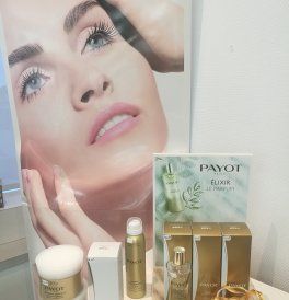 Des produits cosmétiques de soin de la peau présentés devant une affiche représentant le visage d’une femme