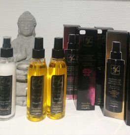 Des flacons et des boîtes de produits capillaires variés sur une étagère, à côté d’une petite statue de Bouddha
