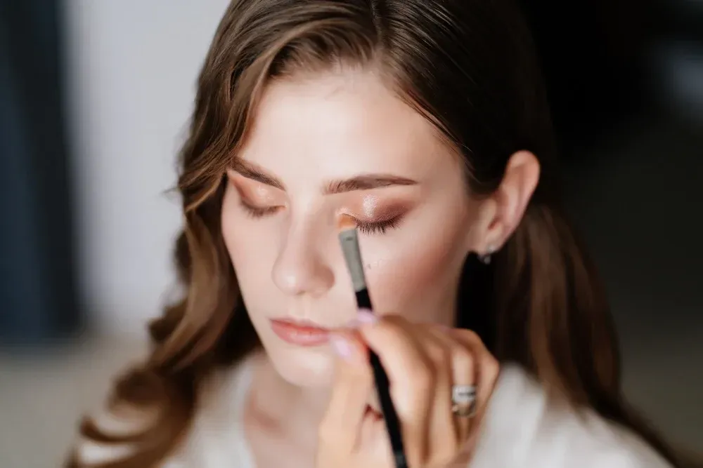 Una mujer se está maquillando con un maquillador.