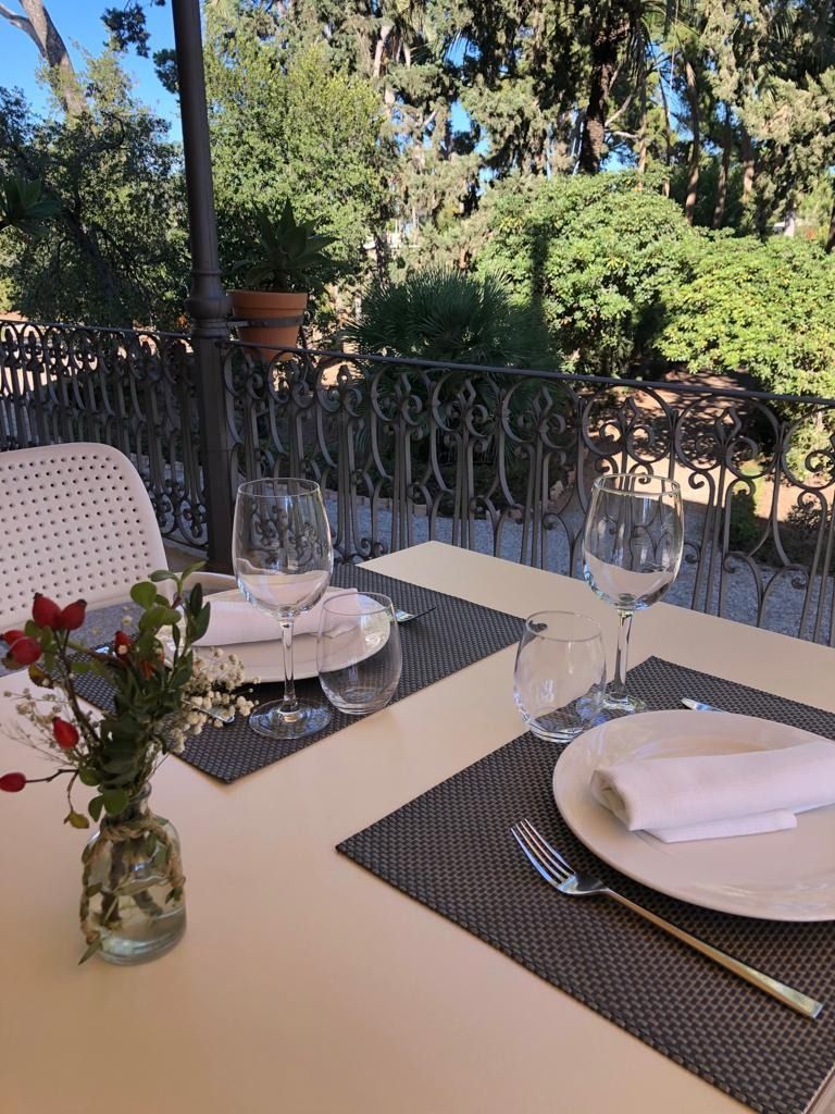 Una mesa con platos, vasos y un jarrón con flores encima.