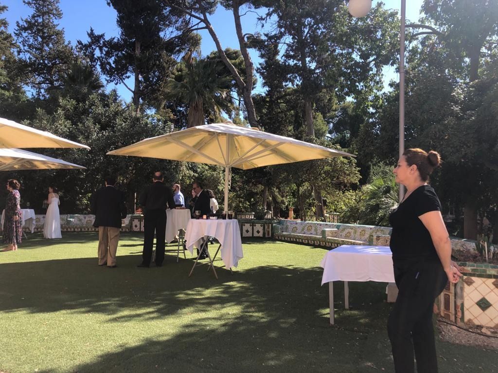 Una mujer está parada en un campo con mesas y sombrillas.