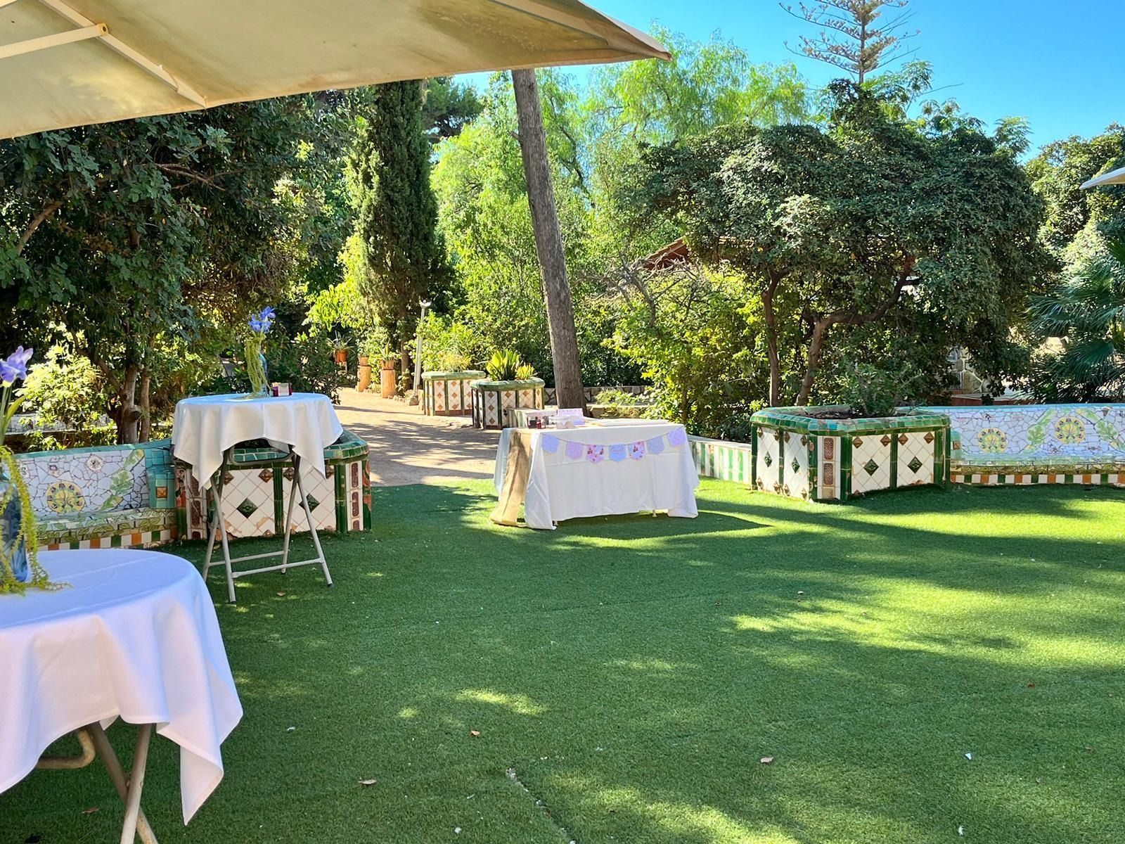Un exuberante campo verde con mesas y sillas preparadas para una fiesta.