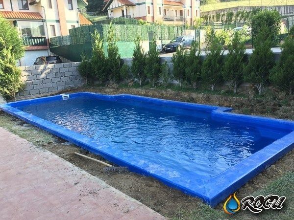 Piscina rectangular azul en un patio residencial.