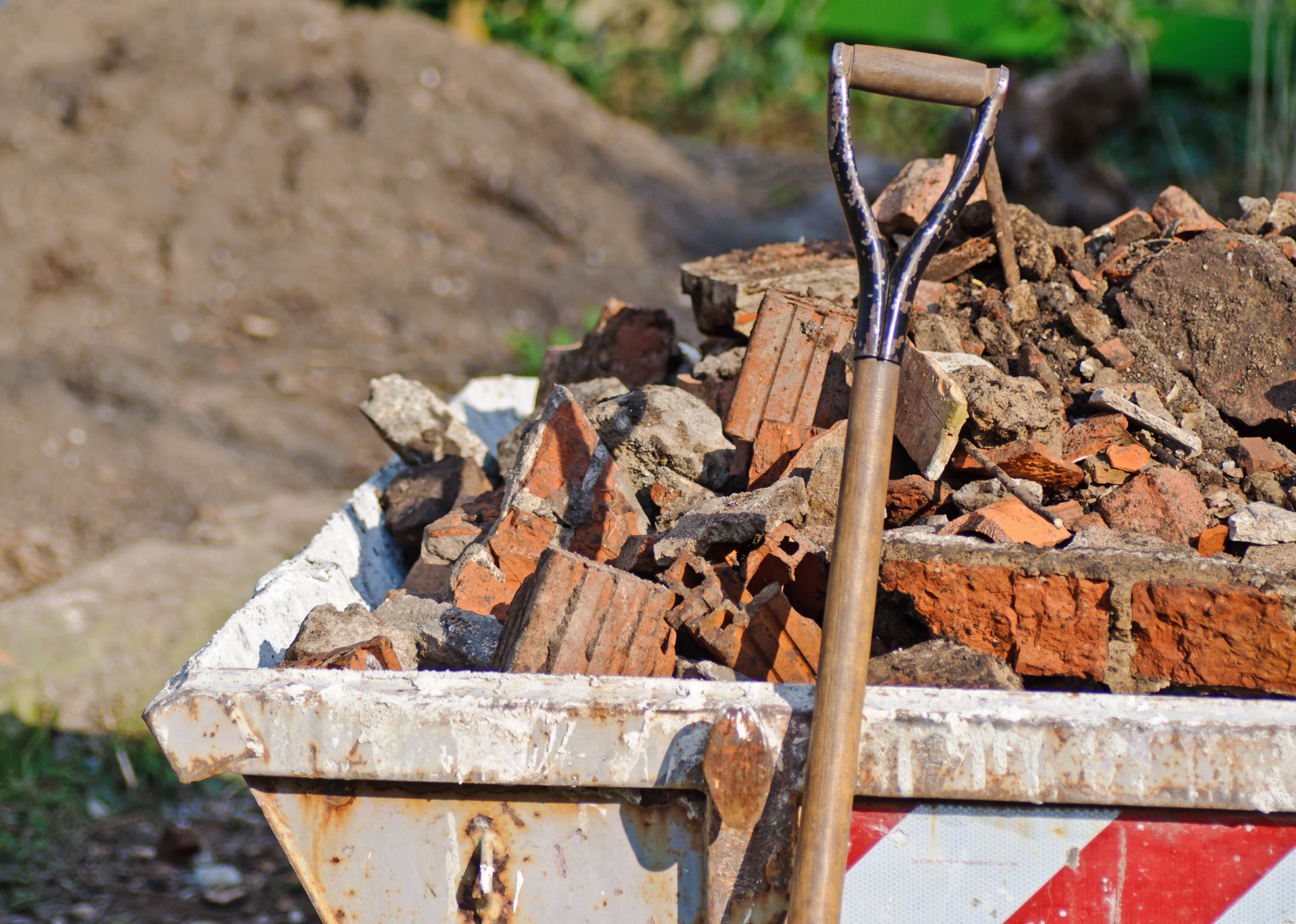 Une benne à gravats de chantier remplie de débris de briques et une pelle.