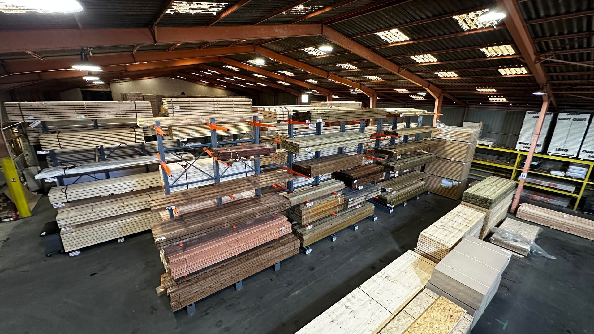 Intérieur d'entrepôt rempli de bois empilé, d'étagères et de cartons.