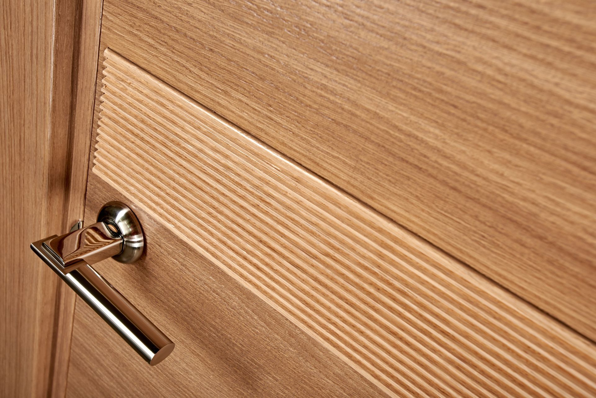 Porte en bois avec poignée argentée. Panneaux en bois clair.