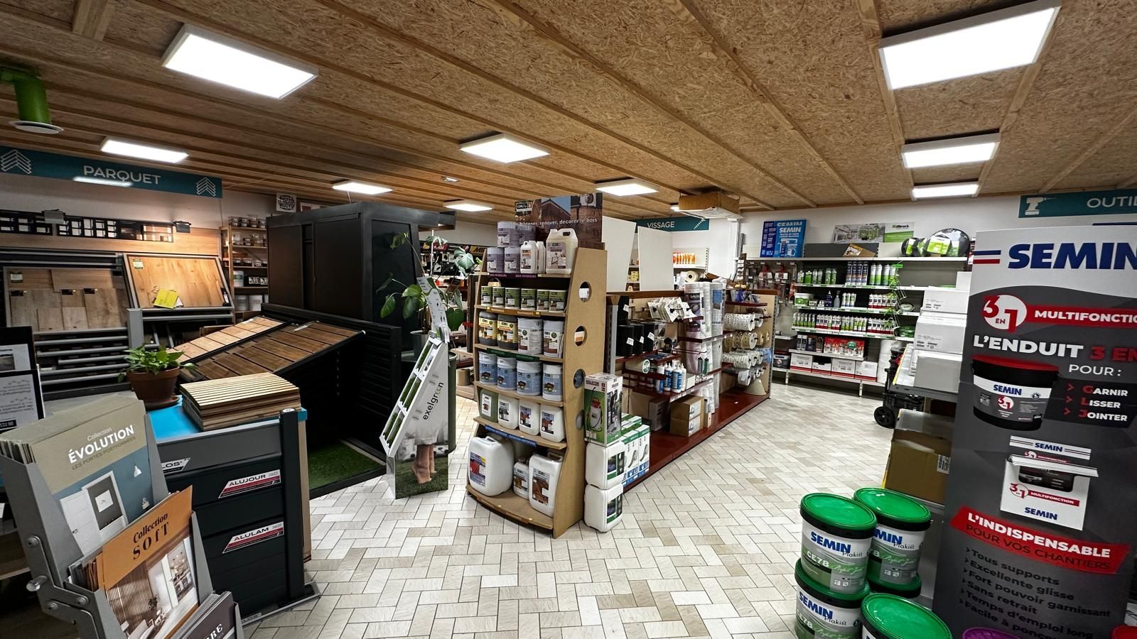 Intérieur d'une quincaillerie avec étagères en bois, produits et comptoir.