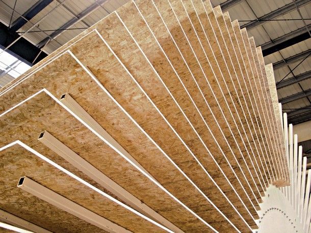 Cuisine en construction avec armoires en bois non finies, îlot et hotte aspirante.