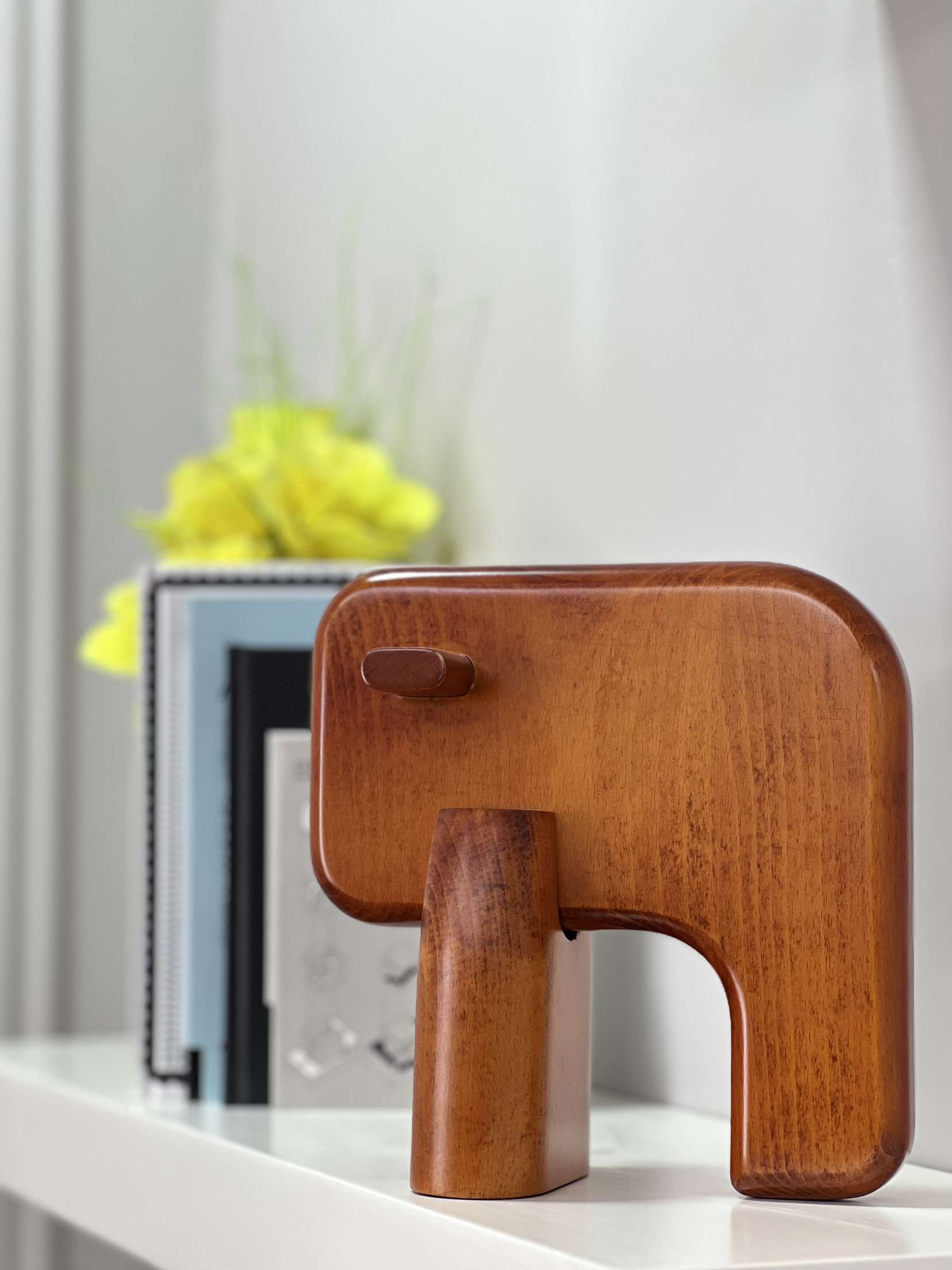 brown elephant minimalist furniture by surjit carpentry and decor with yellow flower, a vase and stack of books at the back of this cute office home decor