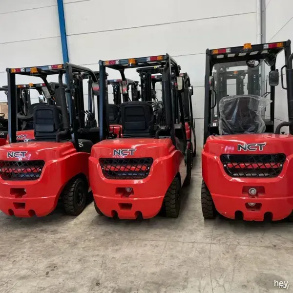 Tres carretillas elevadoras rojas nct están estacionadas en un almacén