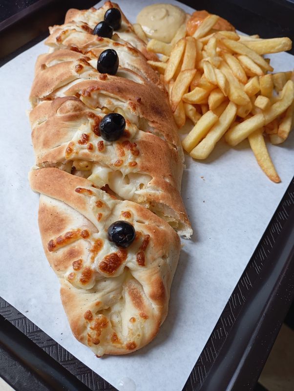 Pain cuit au four farci aux olives noires, servi sur un plateau avec des frites.