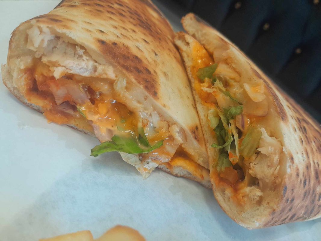 Trois tacos garnis de tomates en dés et de coriandre, servis sur une planche en bois avec du citron vert et de la salsa.