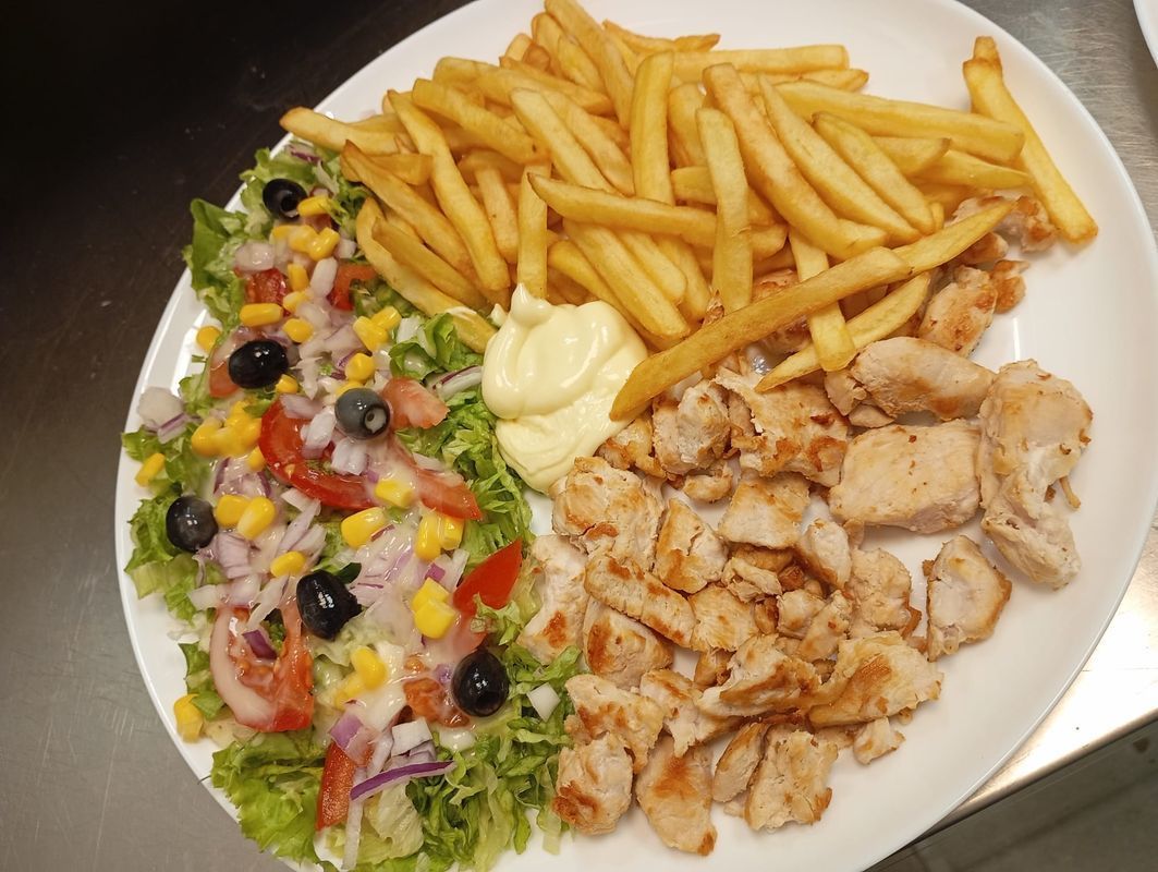 Assiette composée de poulet grillé, de frites et d'une salade fraîche avec olives et tomates.