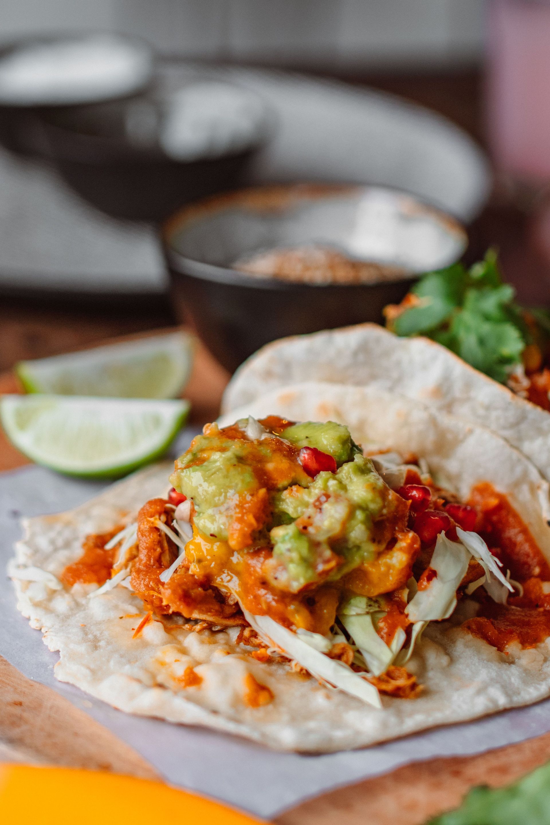 Taco moelleux garni de viande effilochée, de salsa et d'avocat, servi avec des quartiers de citron vert.