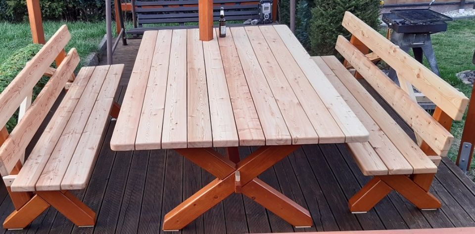 Gartentisch mit Bänken aus Massivholz auf einer Terrasse, im Hintergrund Rasenfläche