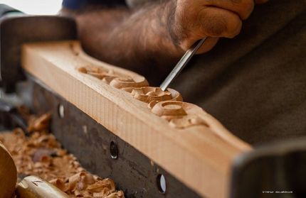 die hand eines Schreiners graviert ein Stück Holz mit Fräsmesser