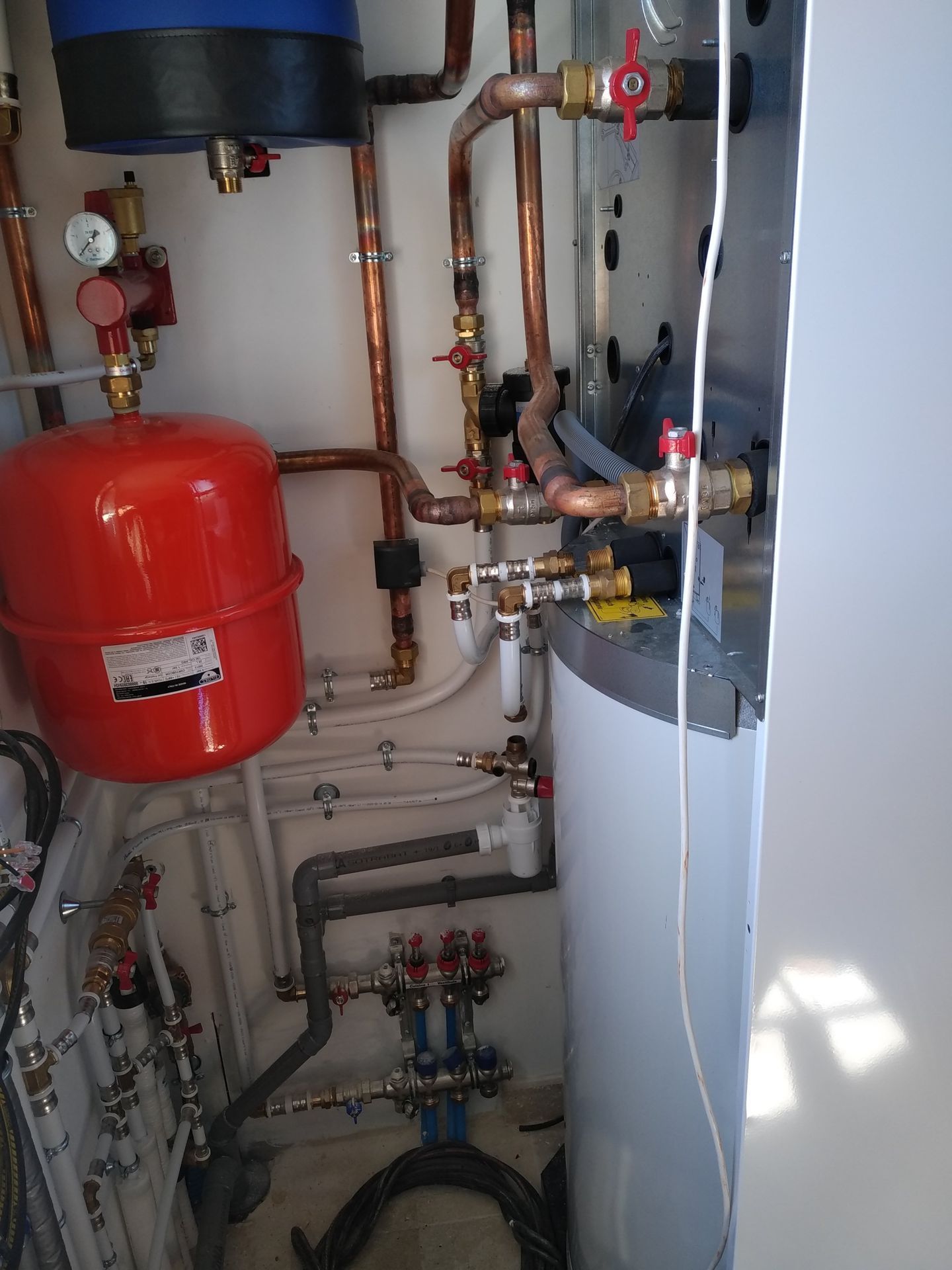Local technique avec des tuyaux en cuivre, un vase d’expansion, un réservoir et un chauffe-eau.