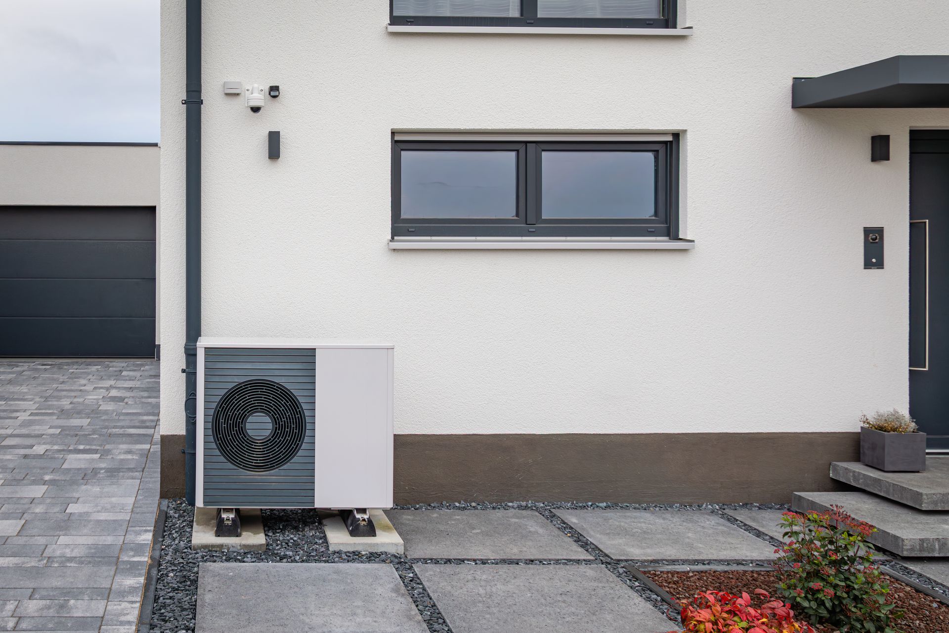 Extérieur d’une maison moderne avec une unité de pompe à chaleur installée à l’extérieur.