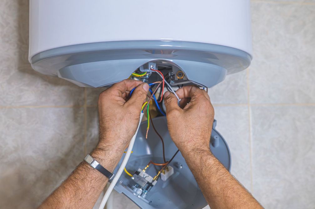 Un technicien raccorde électriquement un appareil installé dans un boîtier.