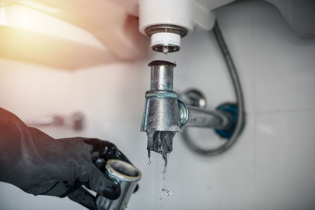 Une main gantée débouche un lavabo.