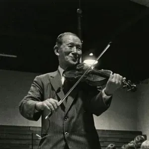 Un hombre de traje toca un violín en una foto en blanco y negro.