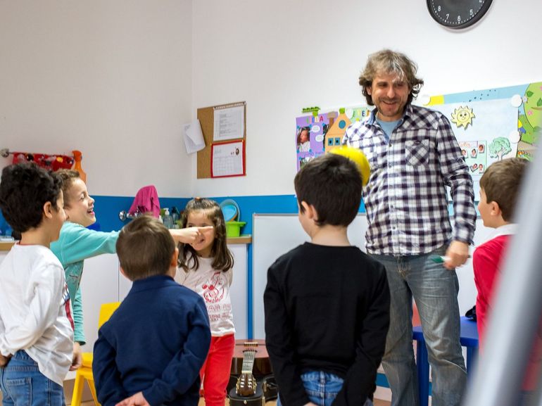 Un grupo de niños está jugando con un hombre con una camisa a cuadros.