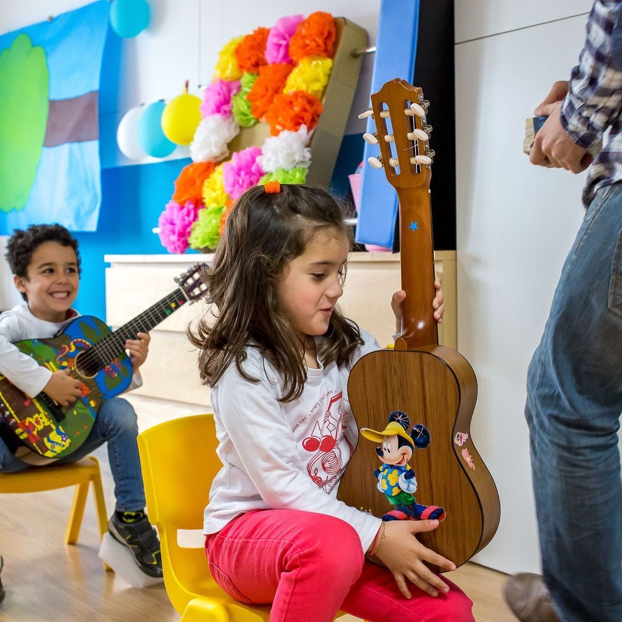 Una niña sostiene una guitarra con una pegatina de Mickey Mouse.