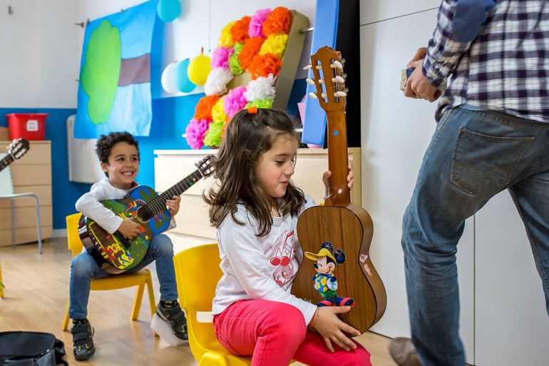 Un niño y una niña están tocando la guitarra en una habitación.