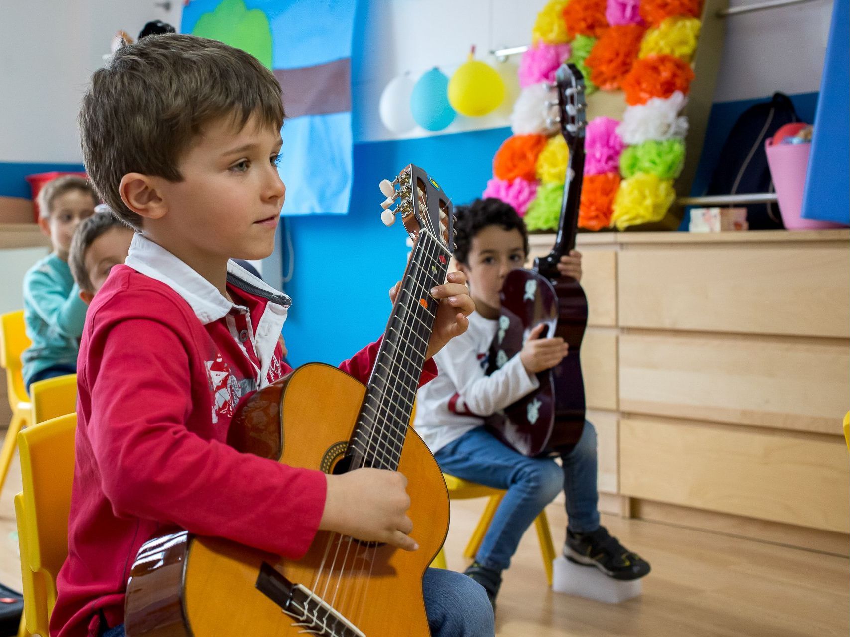 Un grupo de niños pequeños tocan la guitarra en un aula.