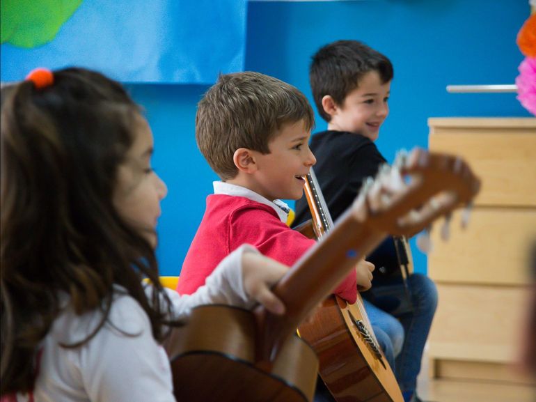 Un grupo de niños está tocando la guitarra en un aula.