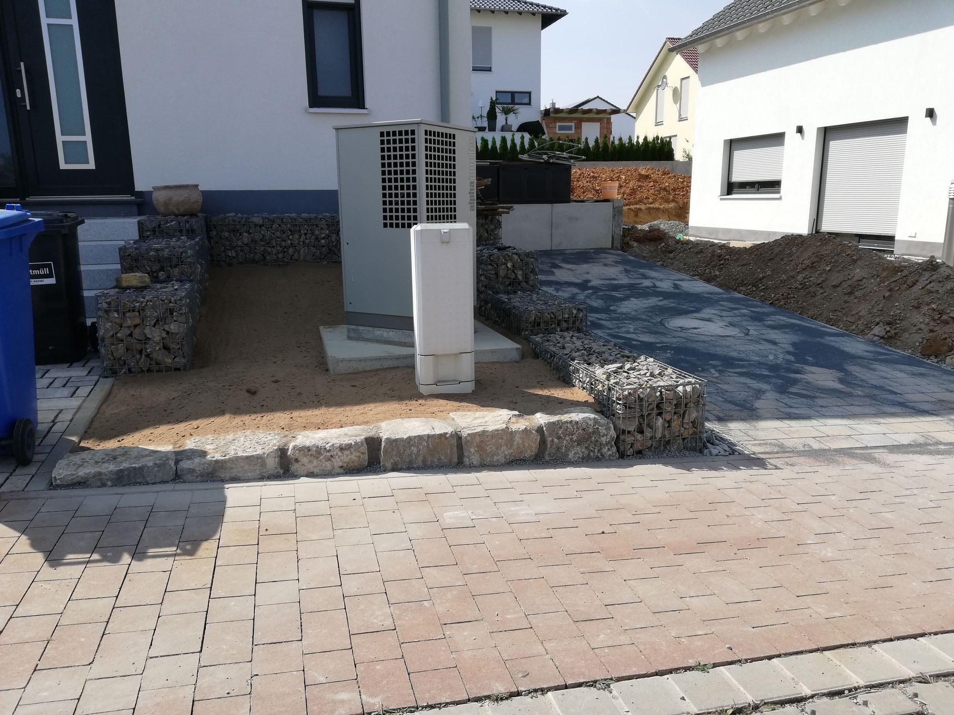 Bau der Zufahrt mit Pflastersteinen, Stützmauern und Kies.